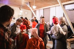 Nainen punaisessa paidassa jakaa riisipuuroa jonottajille.