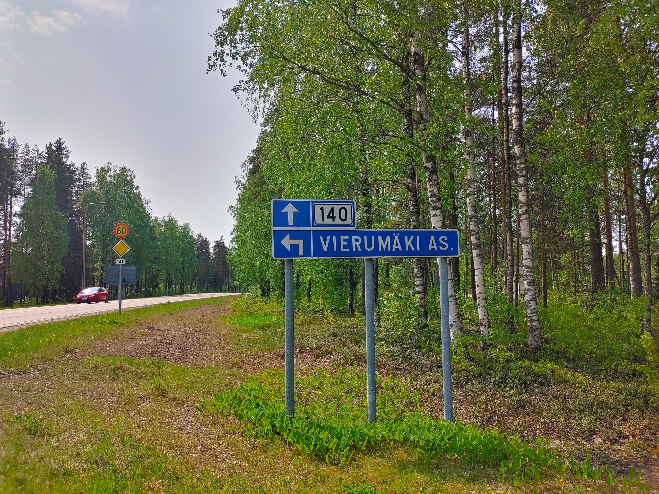 Vierumäen kyltti tien vieressä, taustalla koivuja ja autotie.